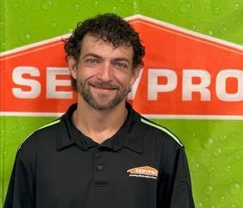 Male Production Tech in black SERVPRO shirt with black and green background