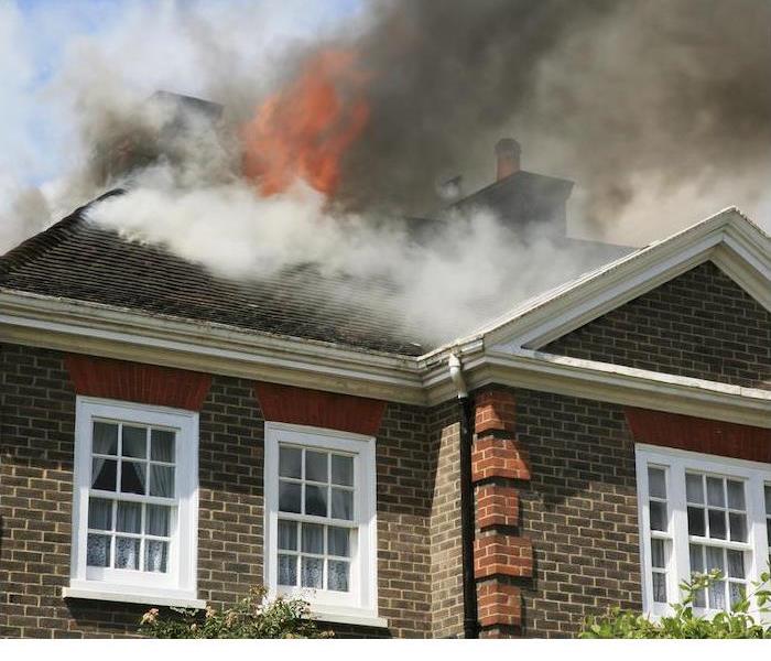 fire and smoke coming out of roof of brown and red brick home